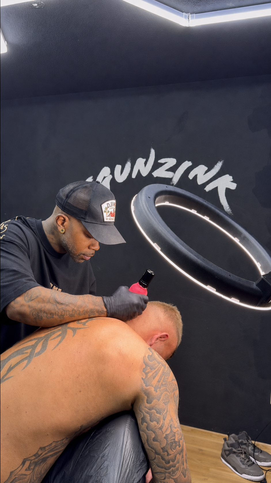 Tommy Gunz tattooing a client at TGUNZINK Tattoo Studio